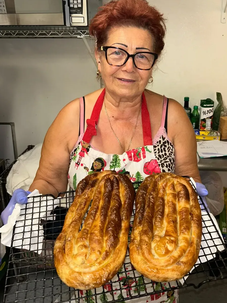 Grandma holding two trays of fresh, golden homemade burek